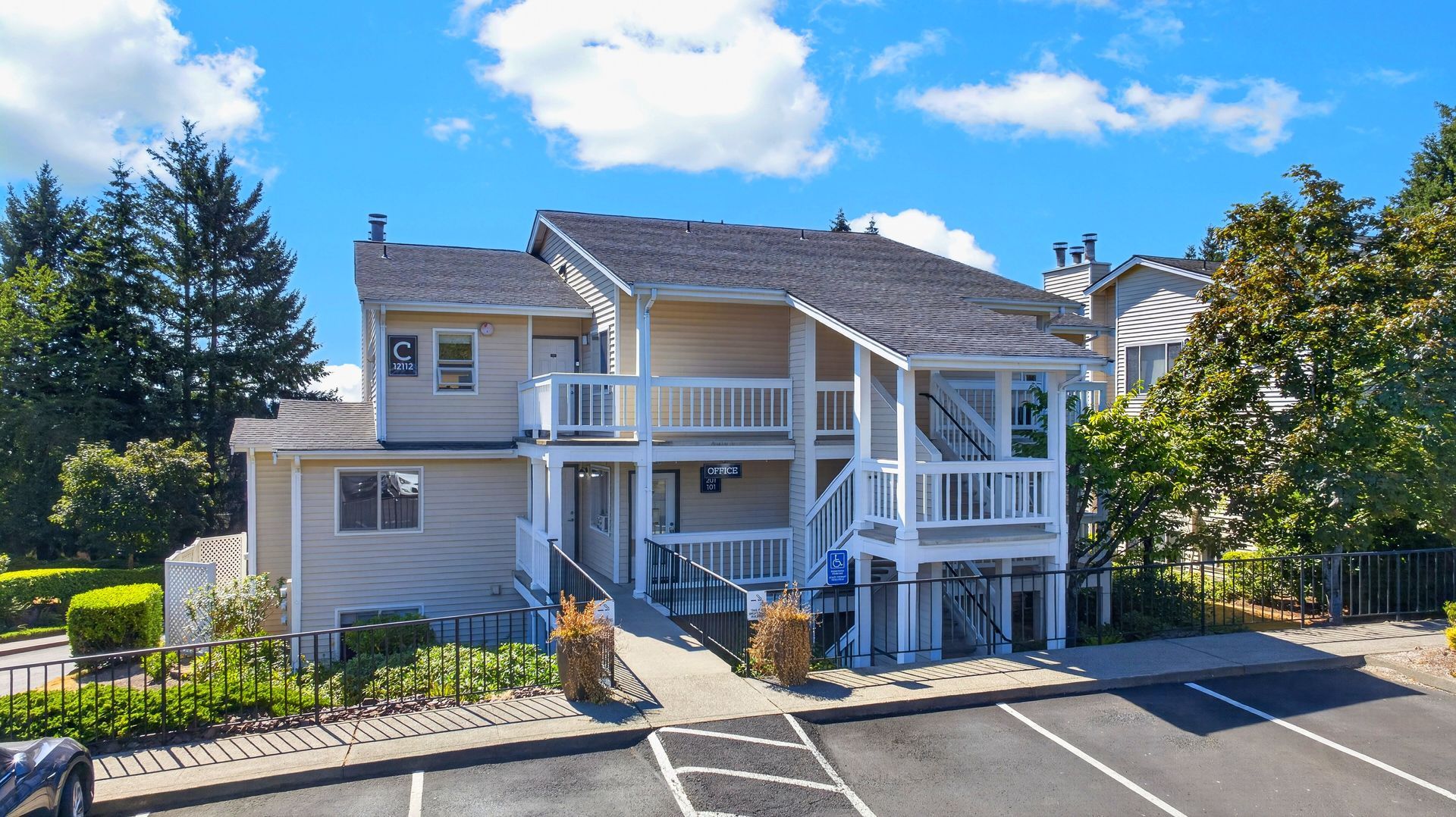 Two-story apartment building with balconies and white railings on a sunny day