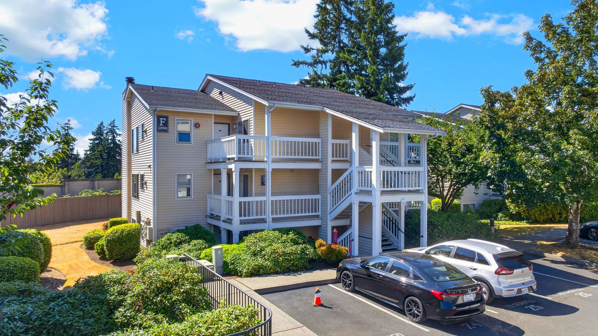 Apartment building with white balconies and parked cars under a bright blue sky