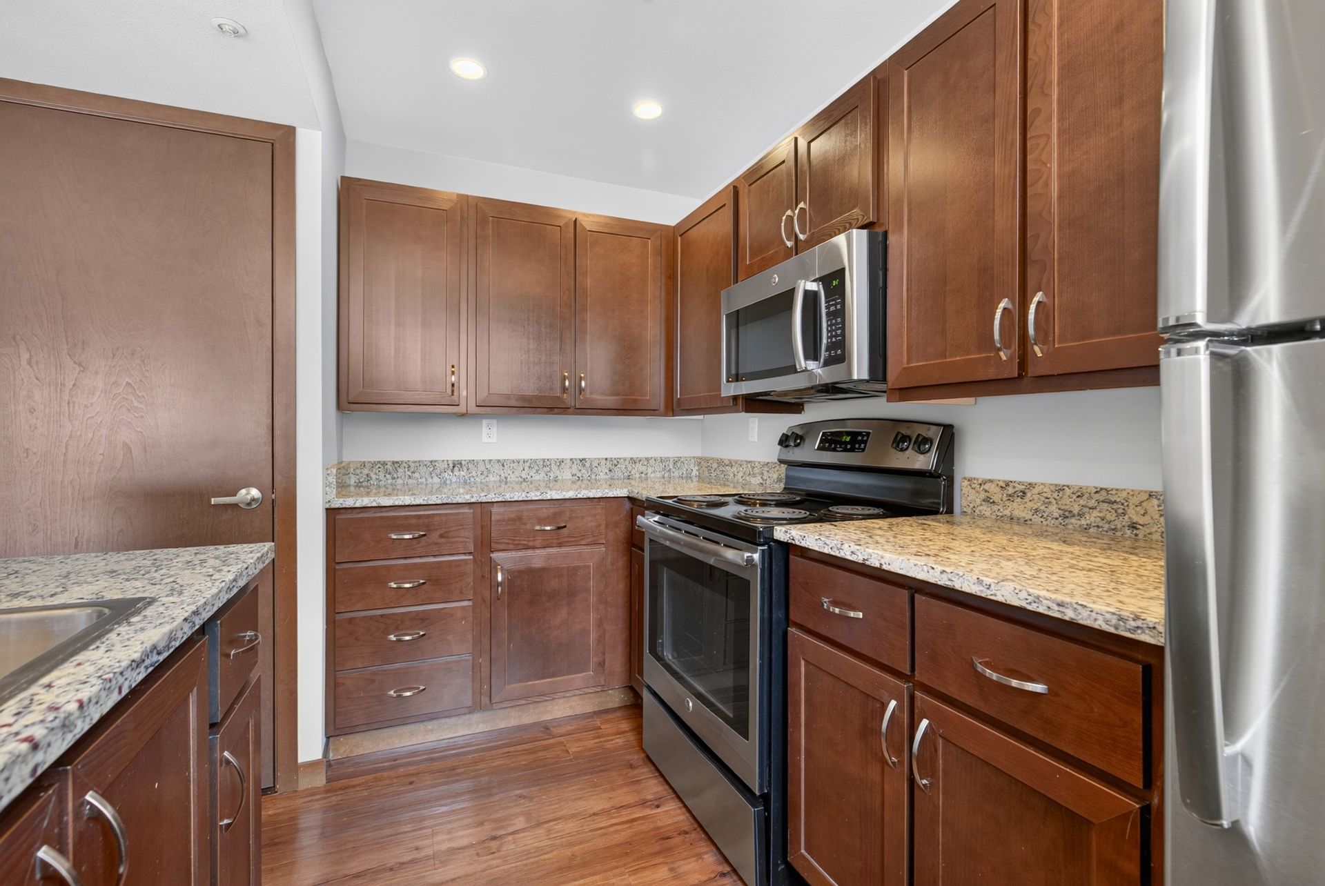 Modern kitchen with wood cabinets, granite countertops, stainless steel appliances, and hardwood floors