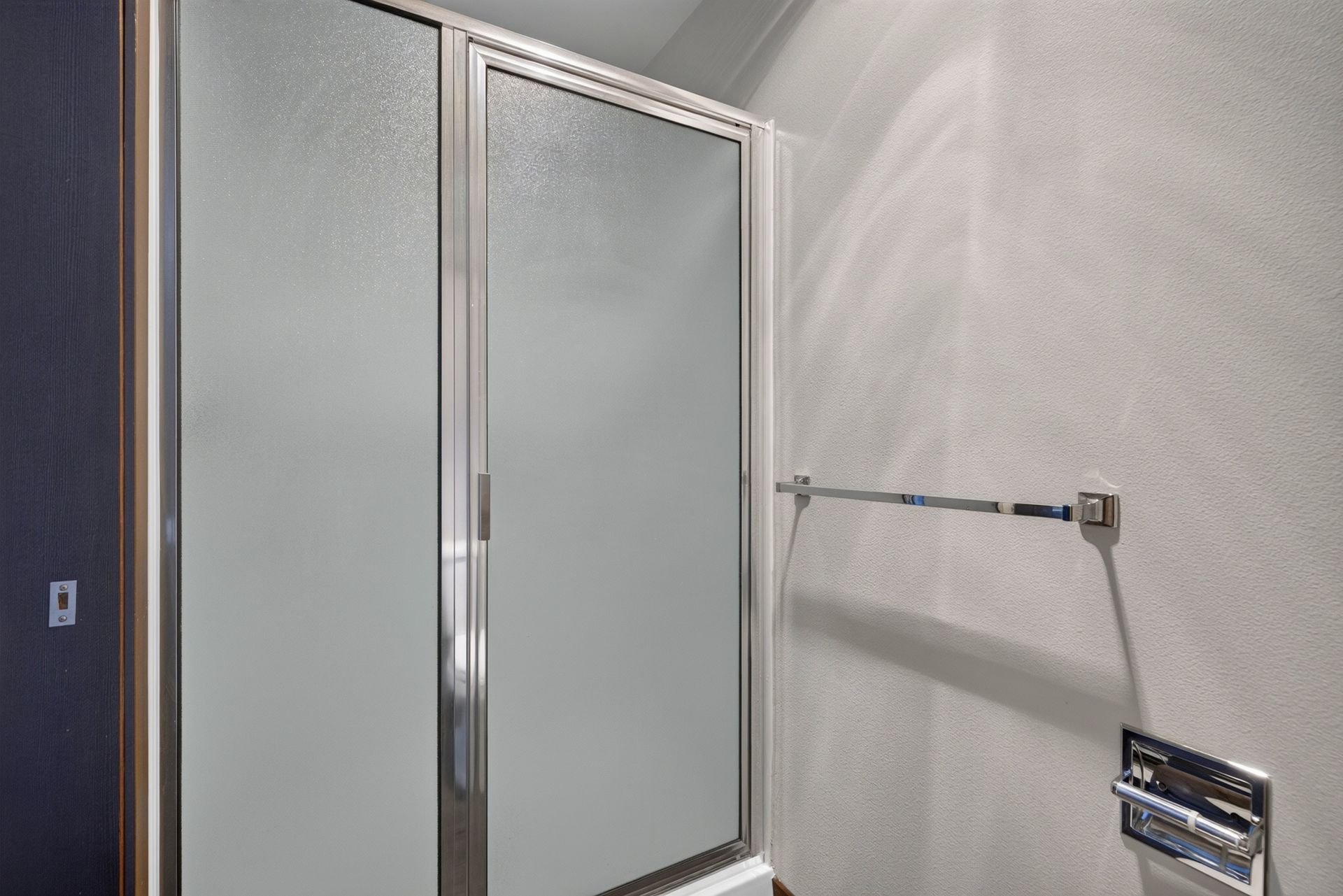 Small bathroom with a frosted glass shower door, wall-mounted towel bar, and chrome fixtures.