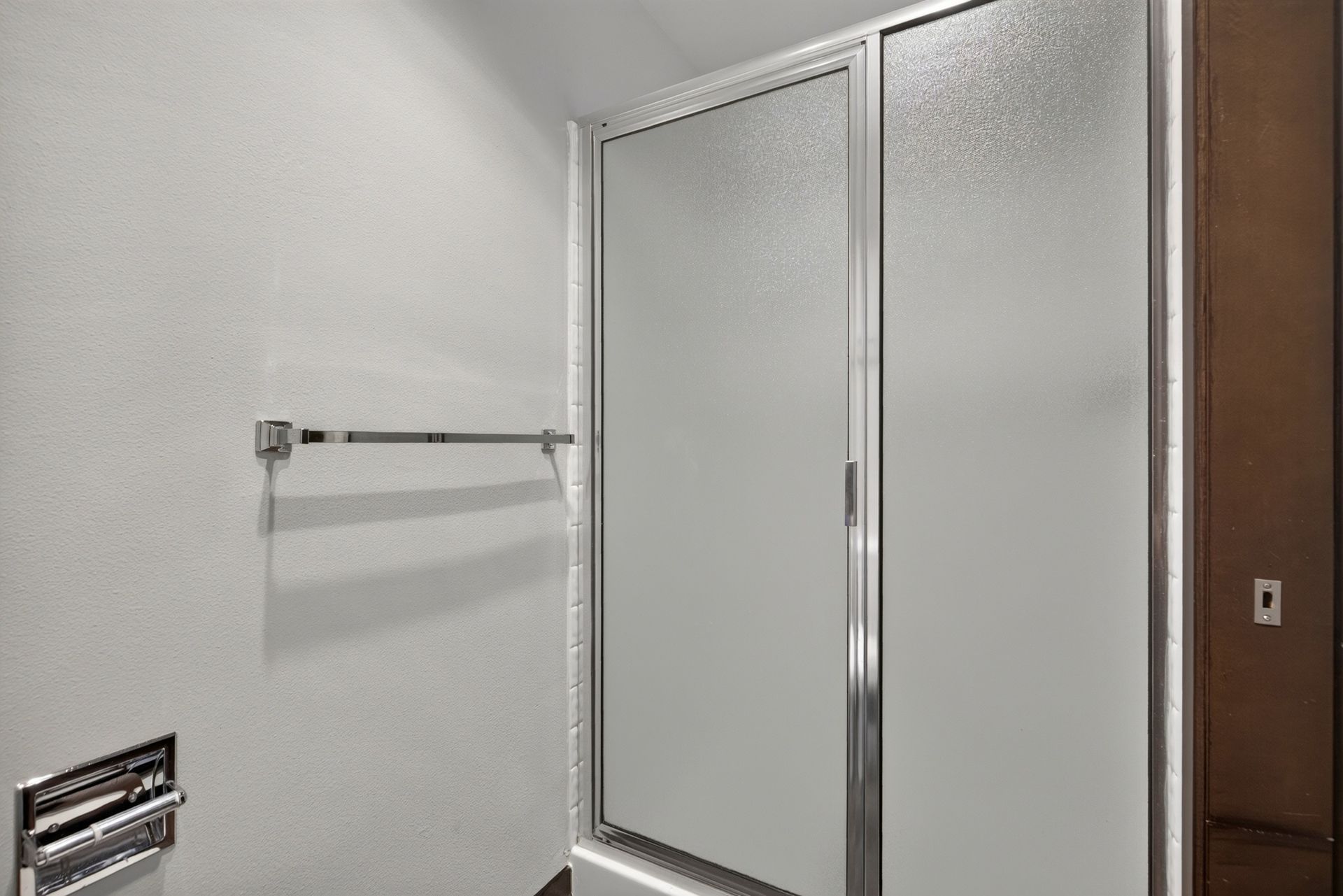 Bathroom with frosted glass shower doors, towel bar, and wall vent