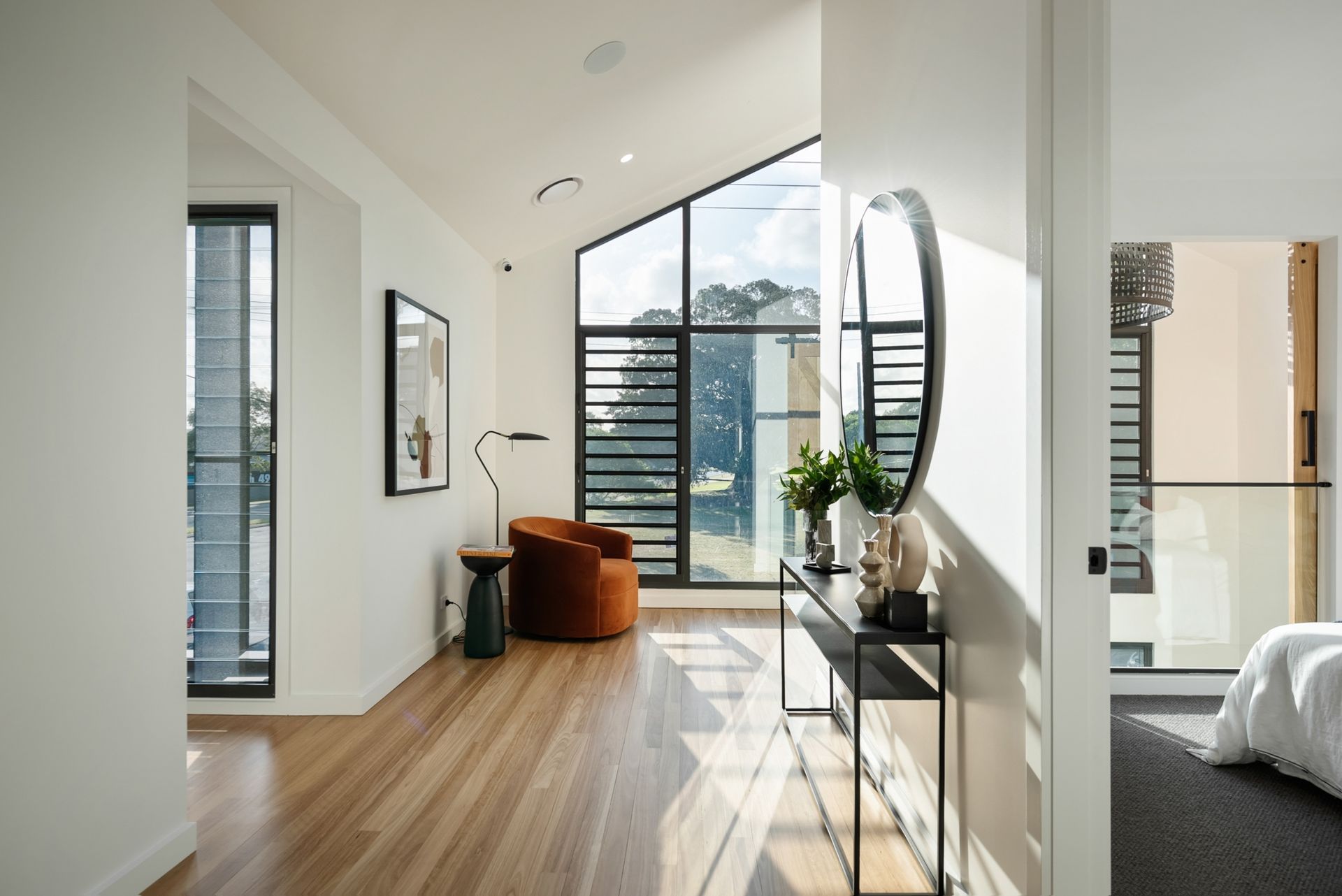 Bright hallway with timber flooring, angled window feature, and styled console table in a Yarrum Designer Homes custom build.