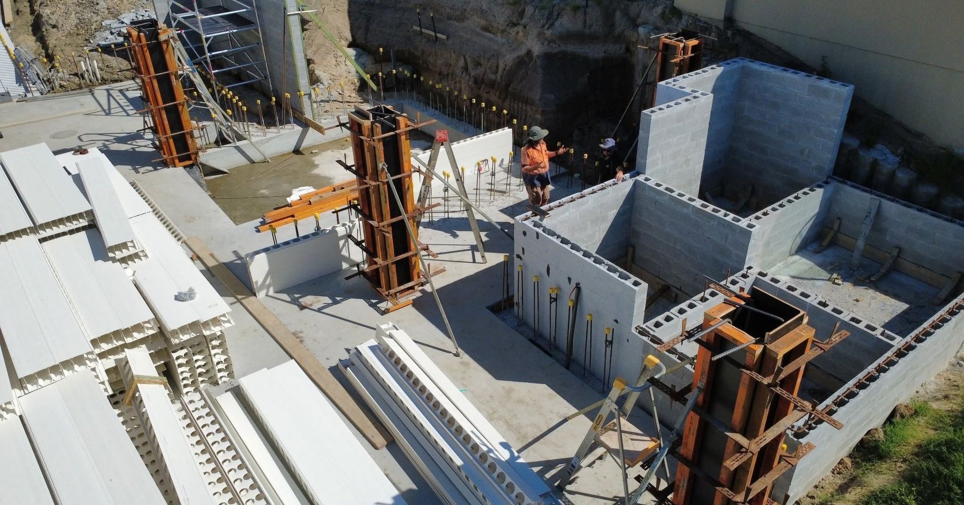 New build Port Macquarie site with block walls, concrete column formwork and two builders reviewing.