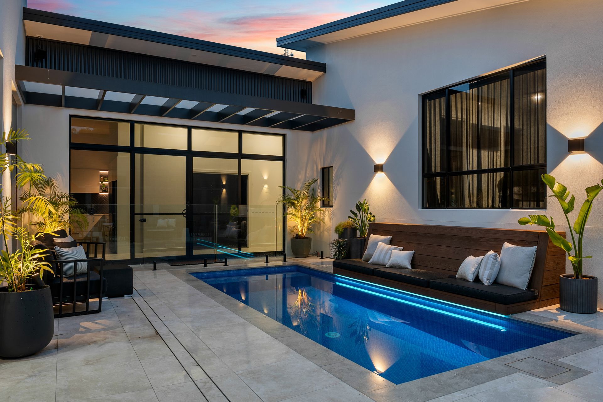 Yarrum custom design home exterior with tiled courtyard, swimming pool, and large glass window