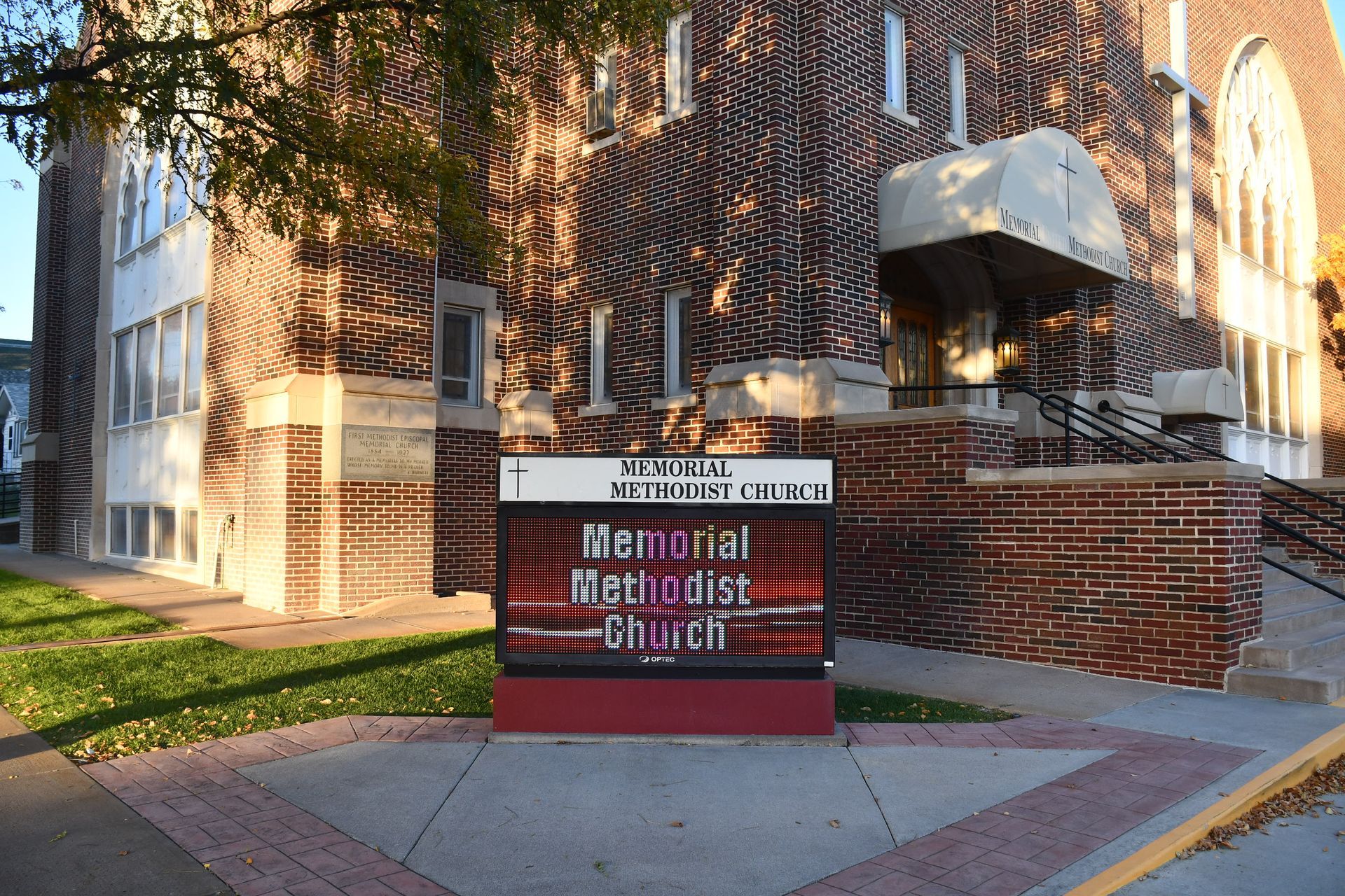 A sign for the Memorial Methodist Church is in front of  brick building.