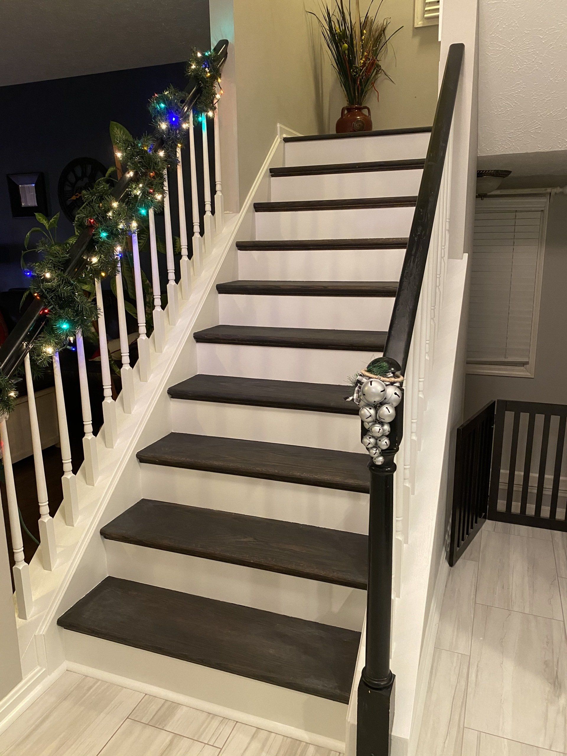 Decorated staircase with garland lights and dark steps in a home interior