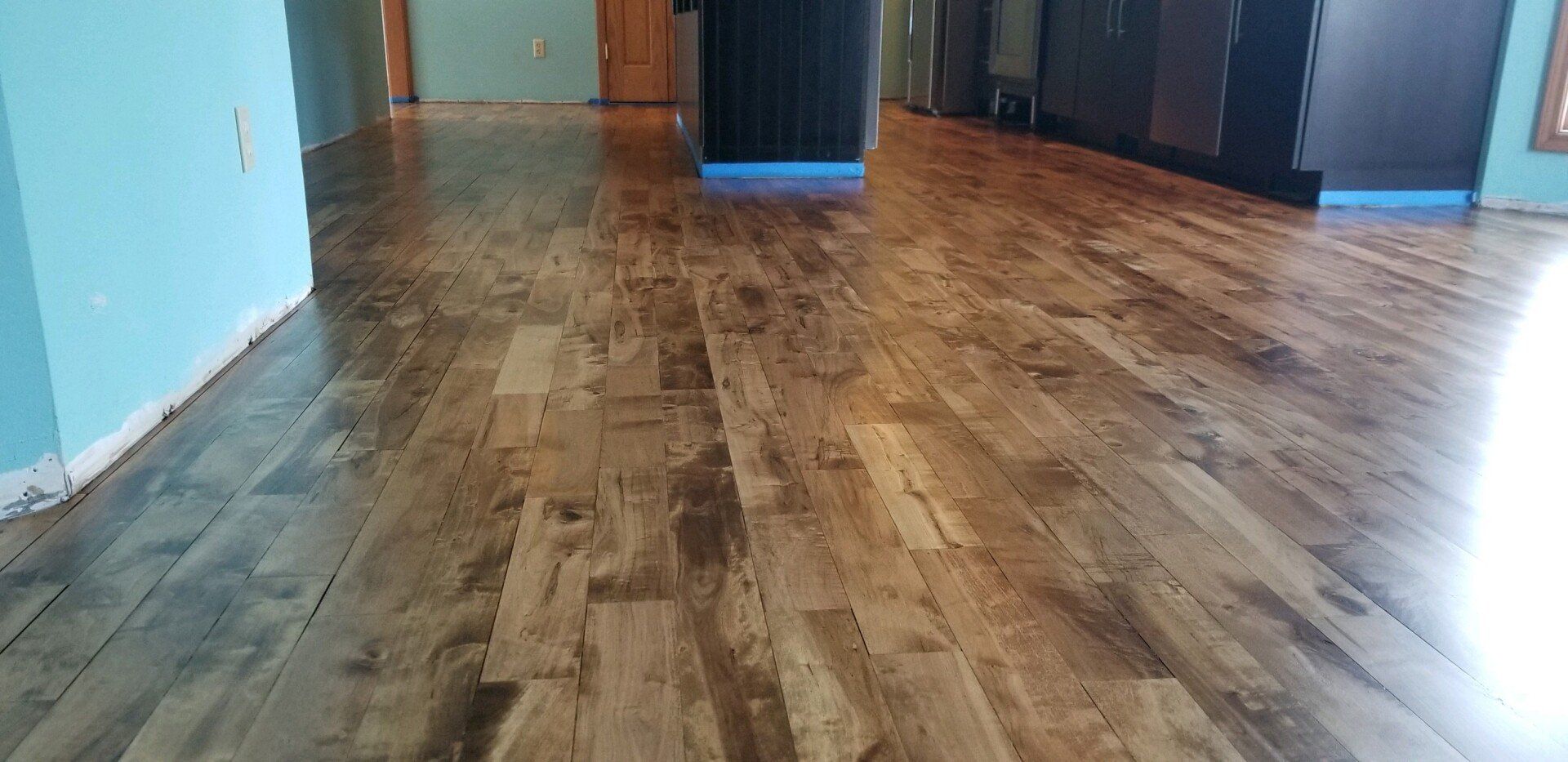 Empty room with glossy wooden floor, blue walls, and cabinets at the back.
