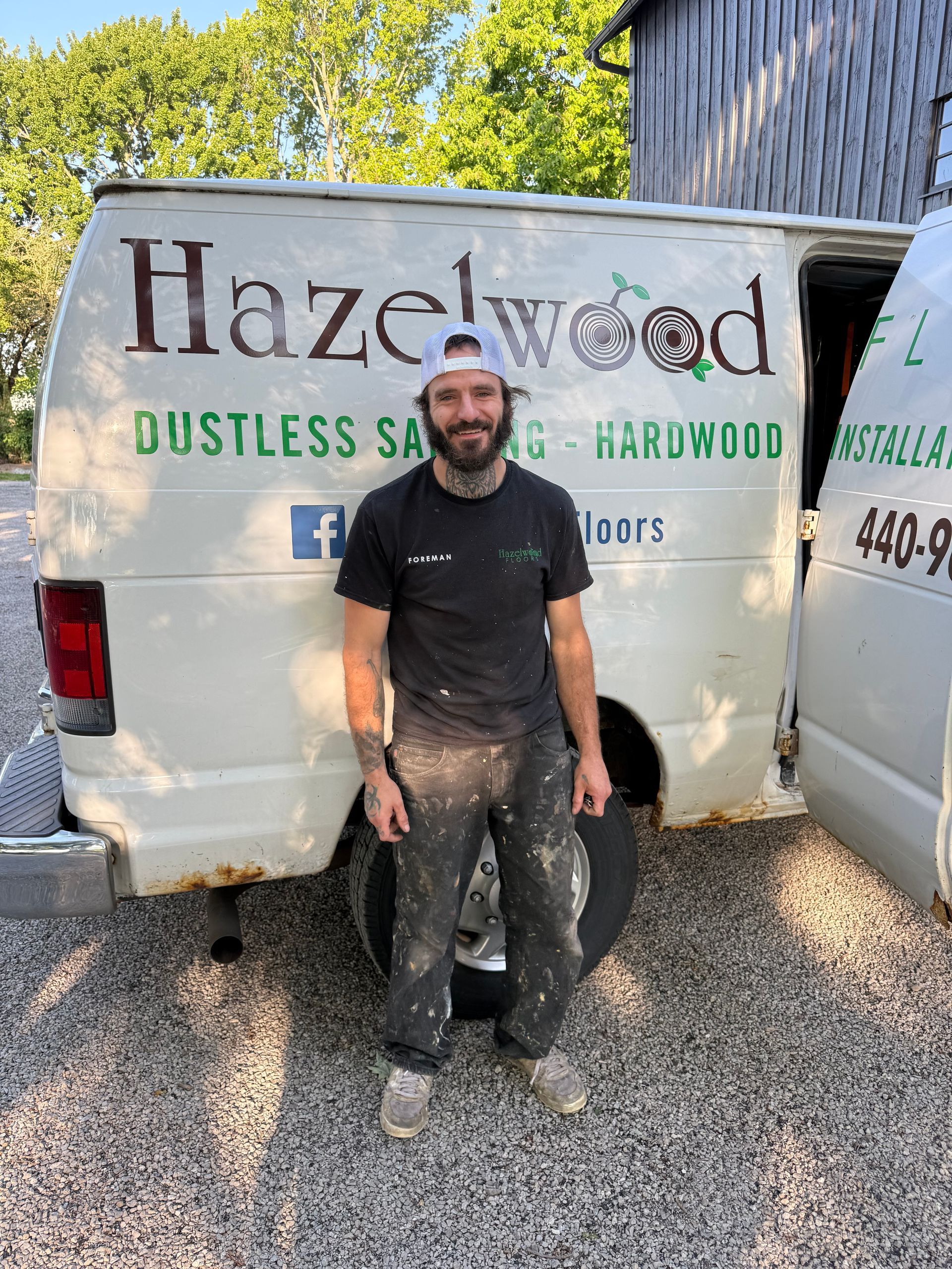 Man standing in front of a Hazlewood U-Haul service van on a gravel lot, covered in mud.
