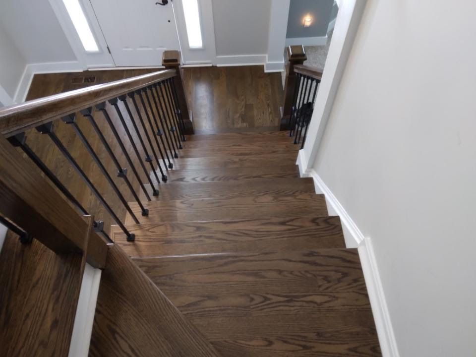 Staircase with dark wood steps, black railing, and white walls in a home interior