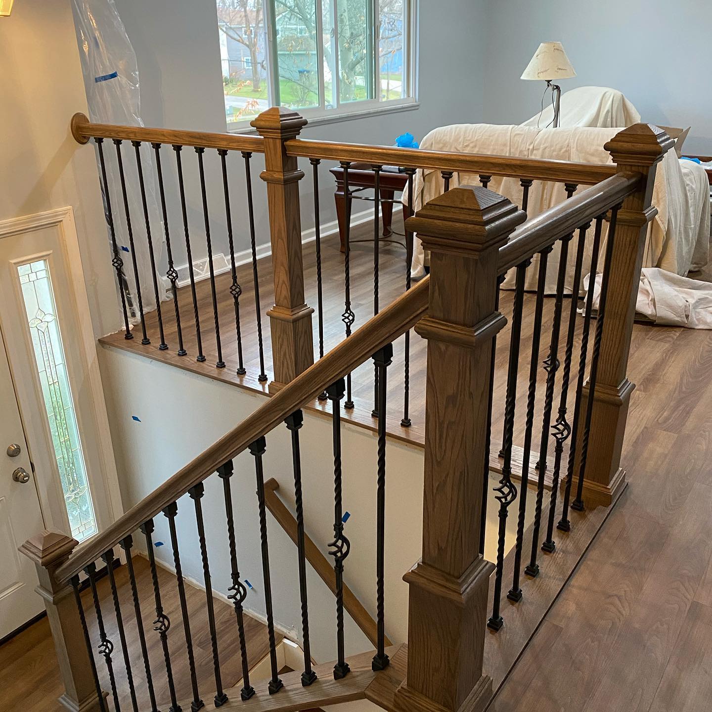 Indoor staircase landing with wooden railing and black balusters beside a bedroom and window.