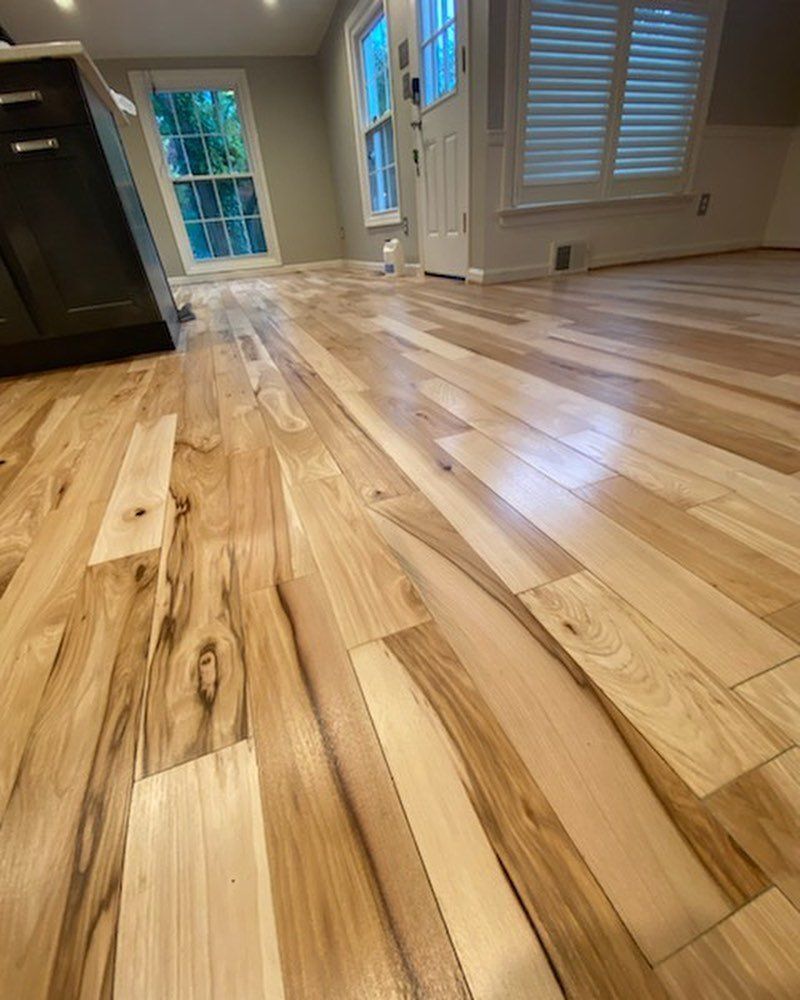 Empty room with glossy light wood floors and bright windows in the background