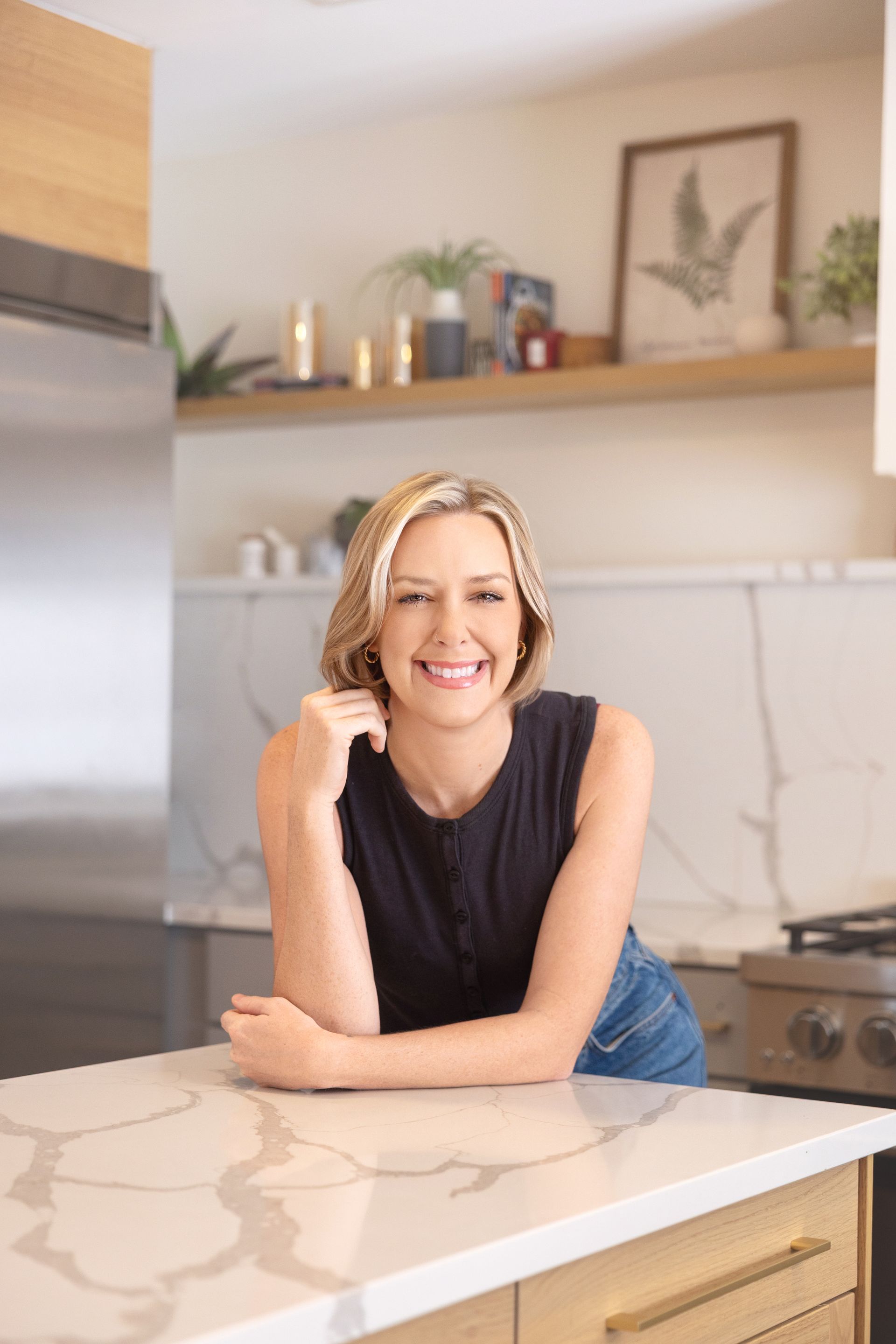 Smiling person leaning on a kitchen counter in a bright, modern kitchen