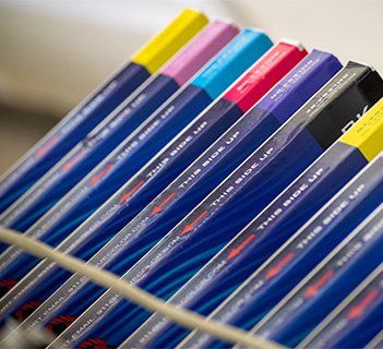 Tilted row of ink cartridges with colorful labels: yellow, pink, blue, red, purple, black.