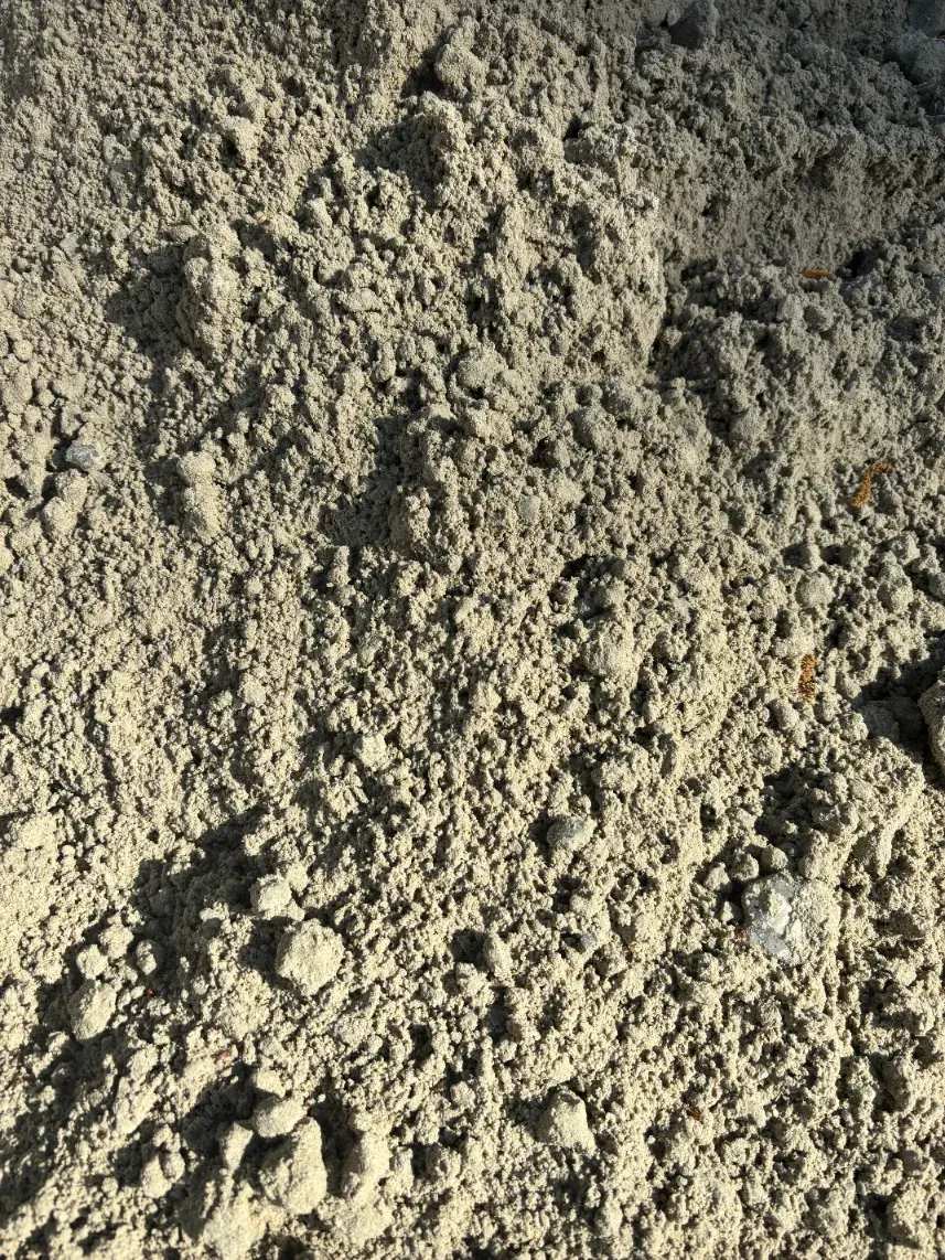 Close-up of rough gray-beige sandy soil with small pebbles and clumps