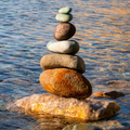 Stack of balanced stones on a wet beach, with rippling water in the background.