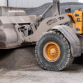 Yellow front loader dumping gravel into a pile at a construction site