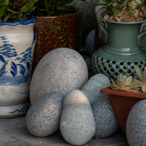 Blue-and-white pots with plants and smooth gray stones arranged on a stone surface