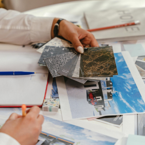 Hands reviewing fabric swatches and house design photos on a table