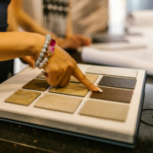 Hand selecting fabric swatches from a color sample board on a table