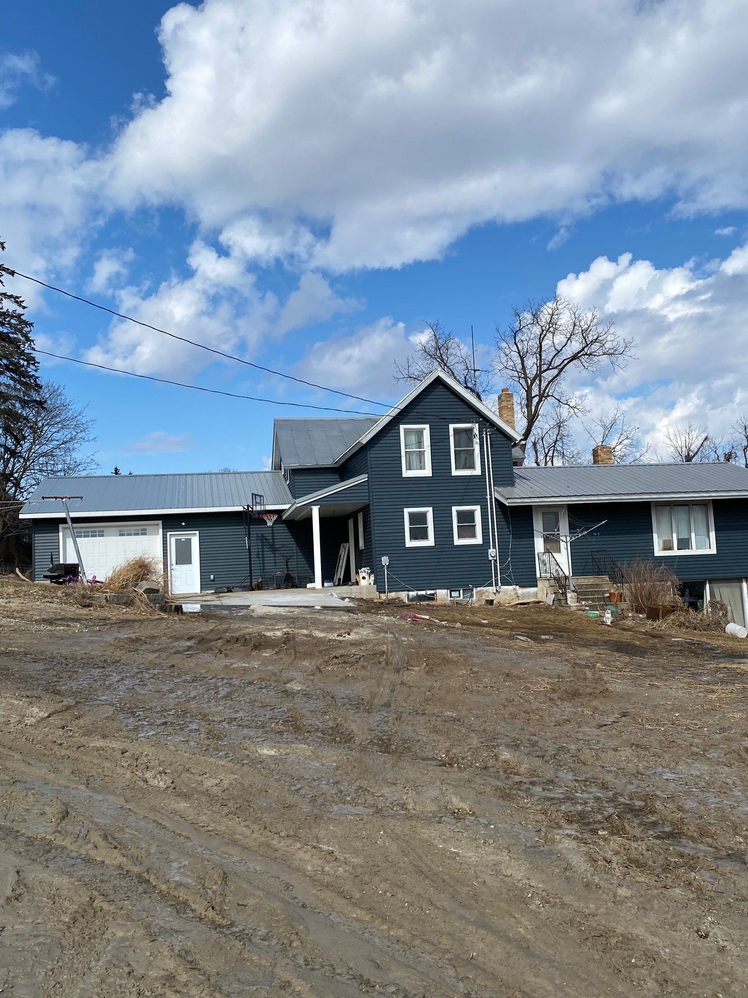 Blue house with white trim, gray roof, and a cloudy sky.