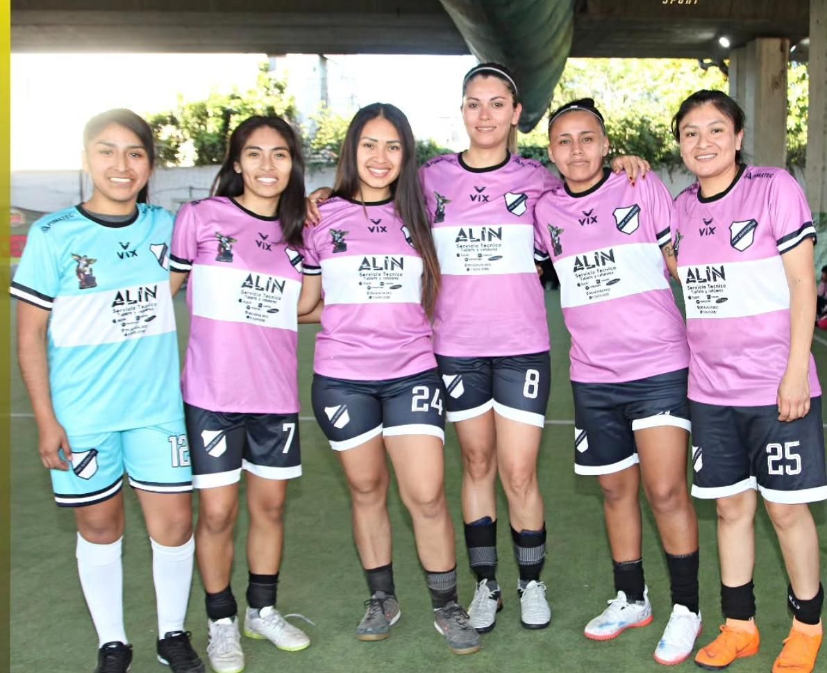 Seis futbolistas con camisetas rosas y turquesas del ALN posando juntos bajo el techo de un estadio.