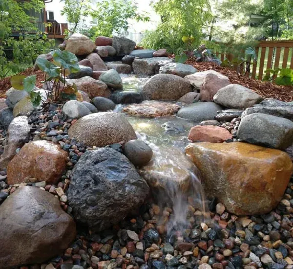 Water feature and pond installation in Loretto MN creating peaceful and decorative backyard landscape elements