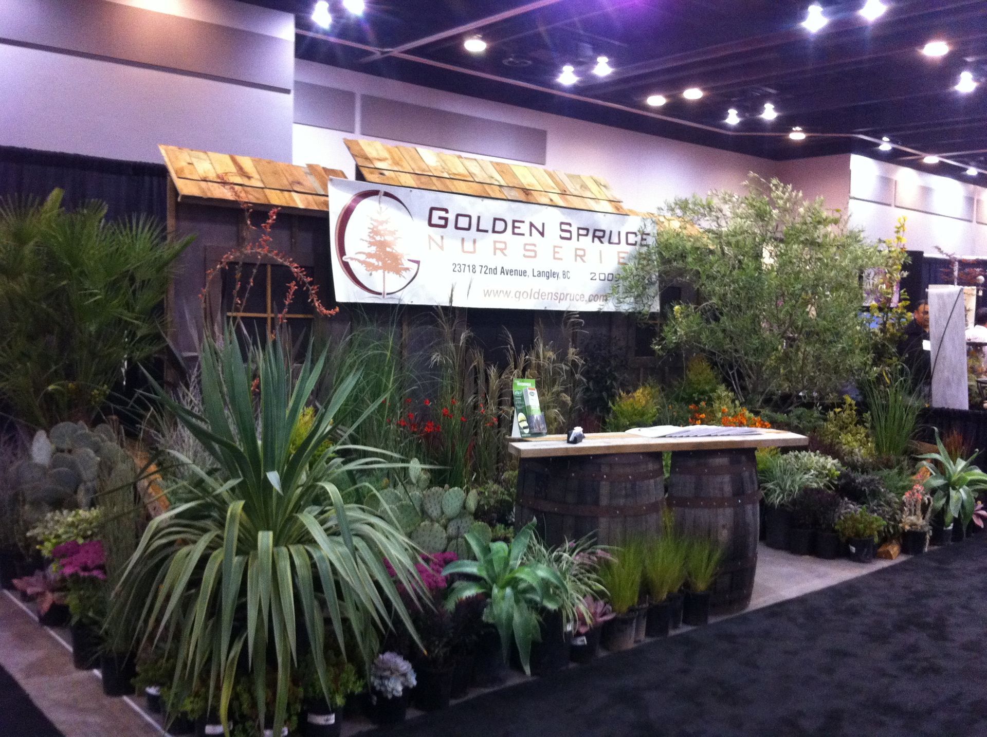 Indoor plant booth with tropical greenery and a Golden Bloom banner at a trade show