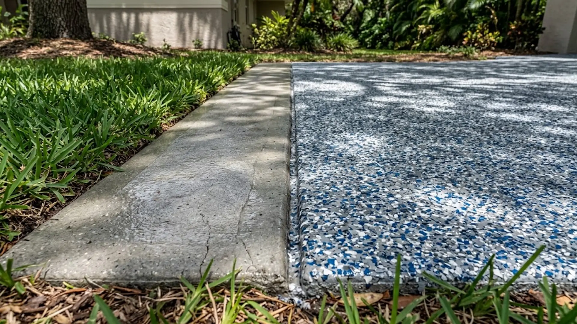 Concrete walkway beside a pebble garden border with green grass in sunlight
