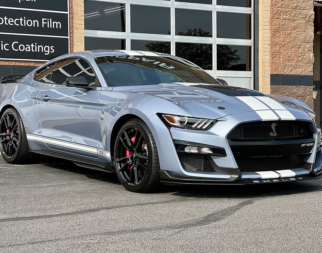 a gray ford mustang is parked in front of a garage door .