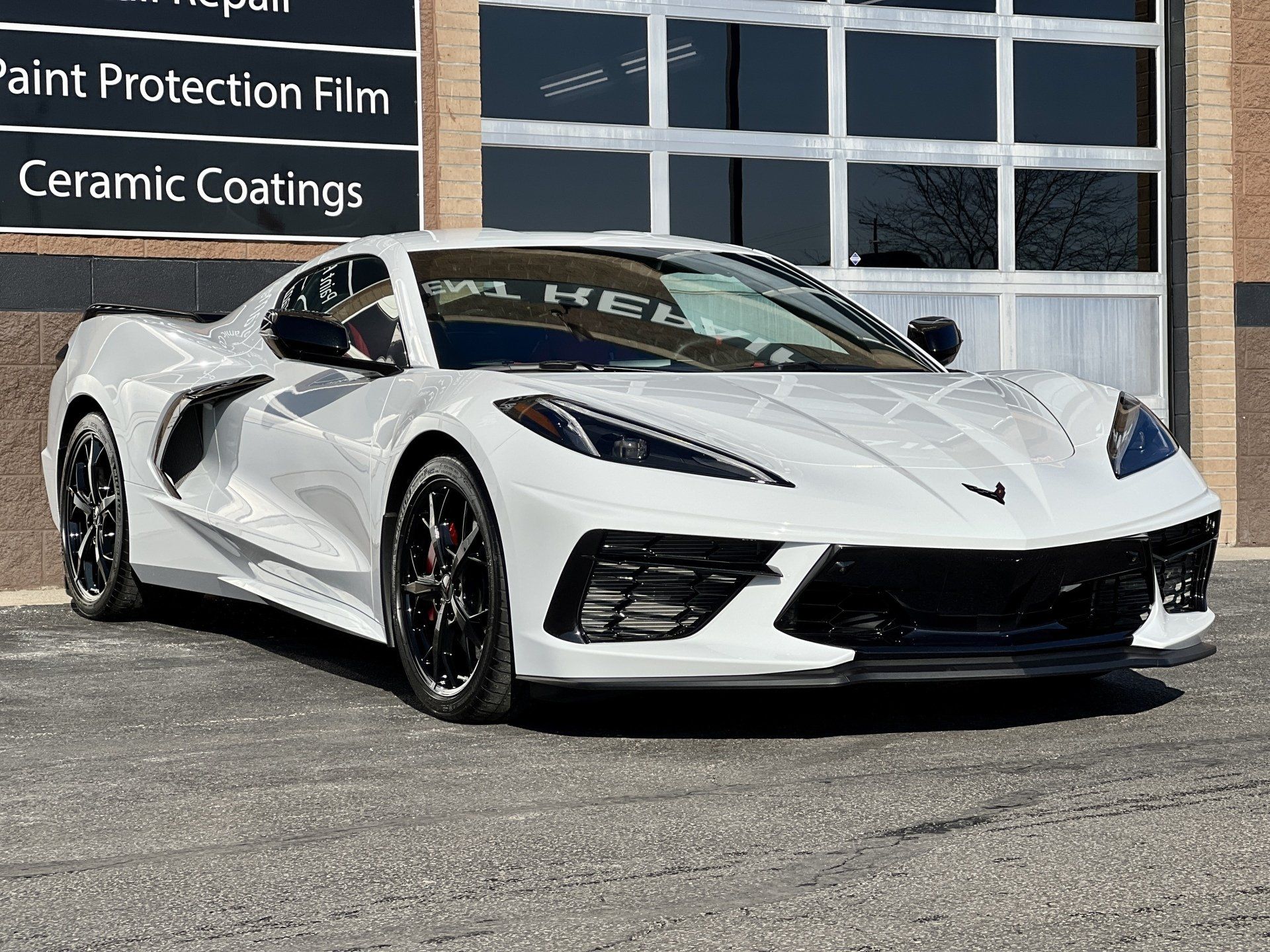 a white corvette is parked in front of a building .