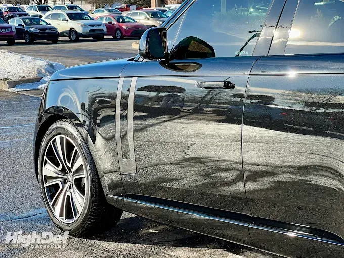 Black car with paint protection film applied, reflecting surroundings for enhanced gloss and protection during summer driving.
