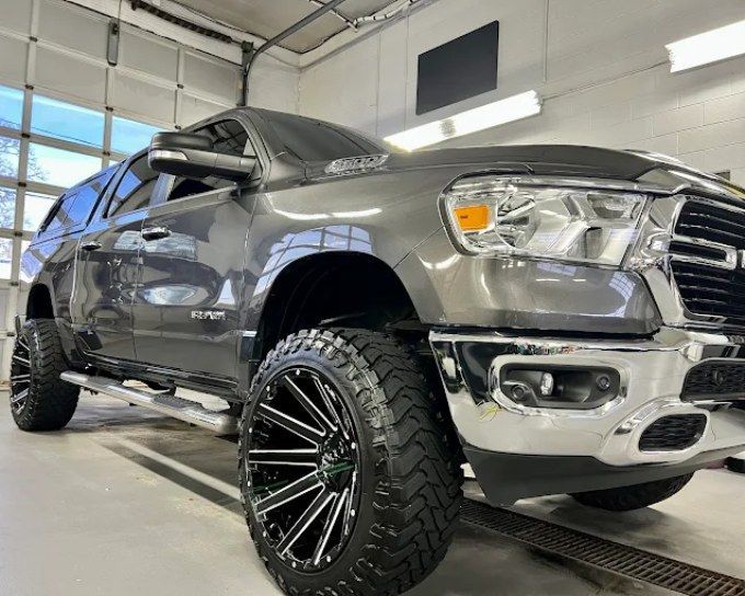 Lifted charcoal gray Ram 1500 truck in shop showing front-end paint protection film coverage options