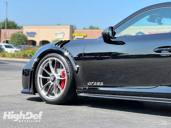 Black sports car with paint protection film on the lower panels and fenders, highlighting protection against road debris and scratches.
