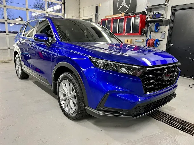 Blue SUV in a garage undergoing paint protection film installation to preserve the paint finish and prevent scratches.