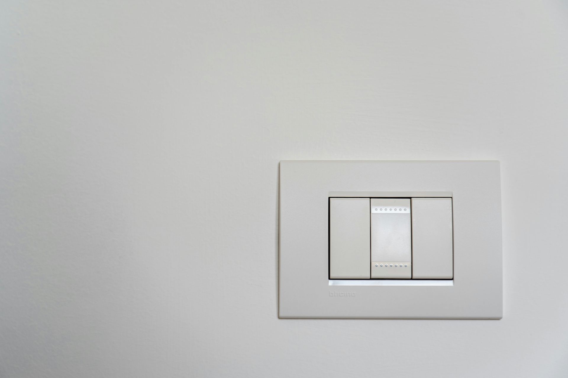 White light switch with three buttons on a white wall.