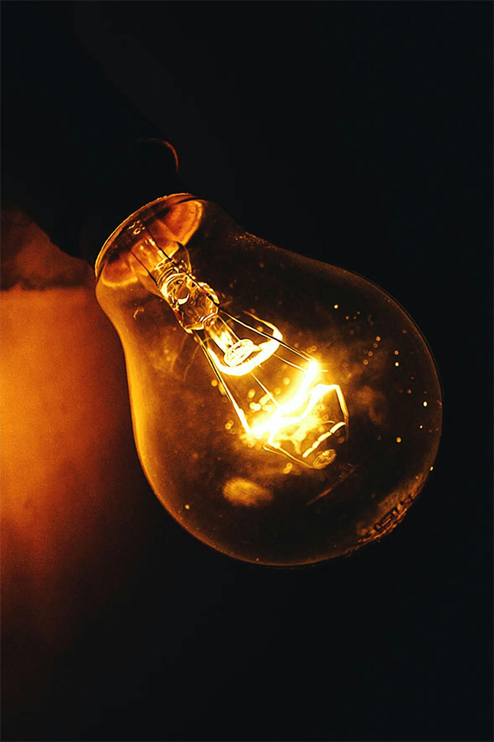 Glowing incandescent light bulb in darkness.