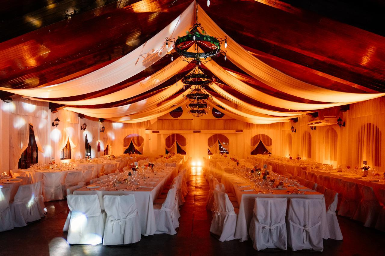 Un salón de banquetes festivo con techo tapizado en tela color crema, luces colgantes 