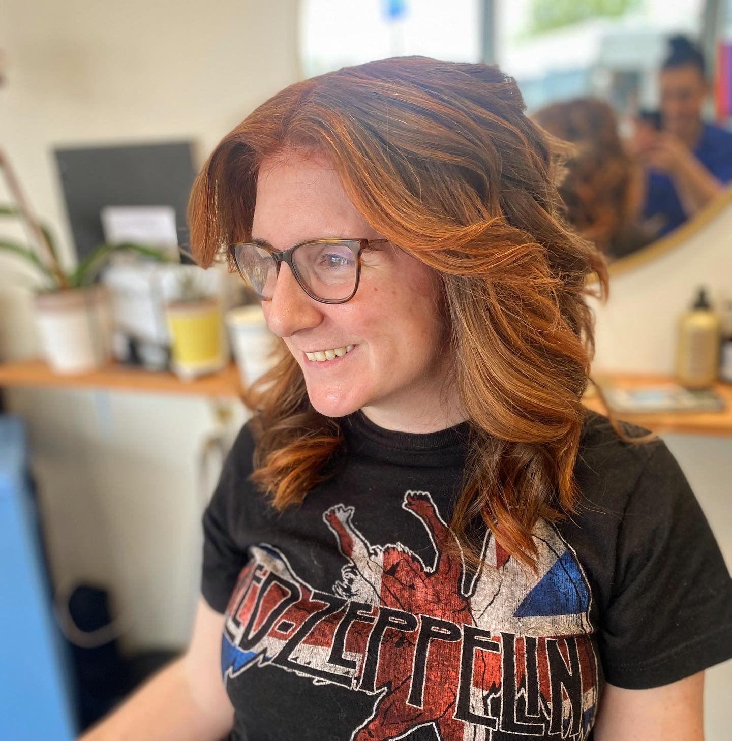 A woman wearing glasses and a zeppelin shirt is smiling