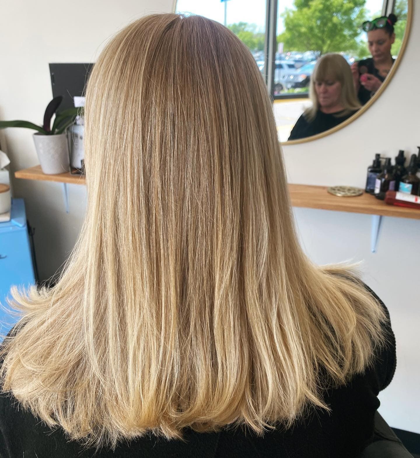 A woman with long blonde hair is sitting in front of a mirror