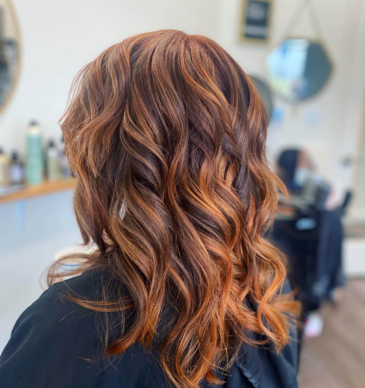 A woman with long red hair is getting her hair done in a salon.