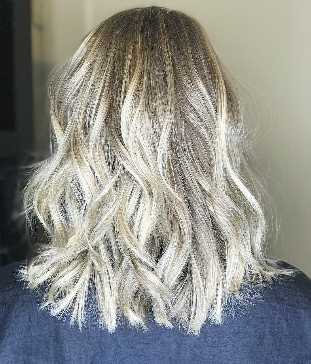 The back of a woman 's head with blonde hair and a blue shirt.