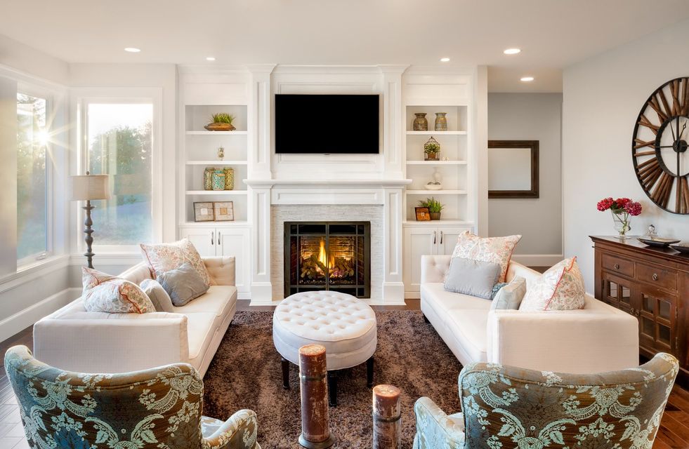 Living room with white sofas, fireplace, TV, built-in shelves, and a large clock.