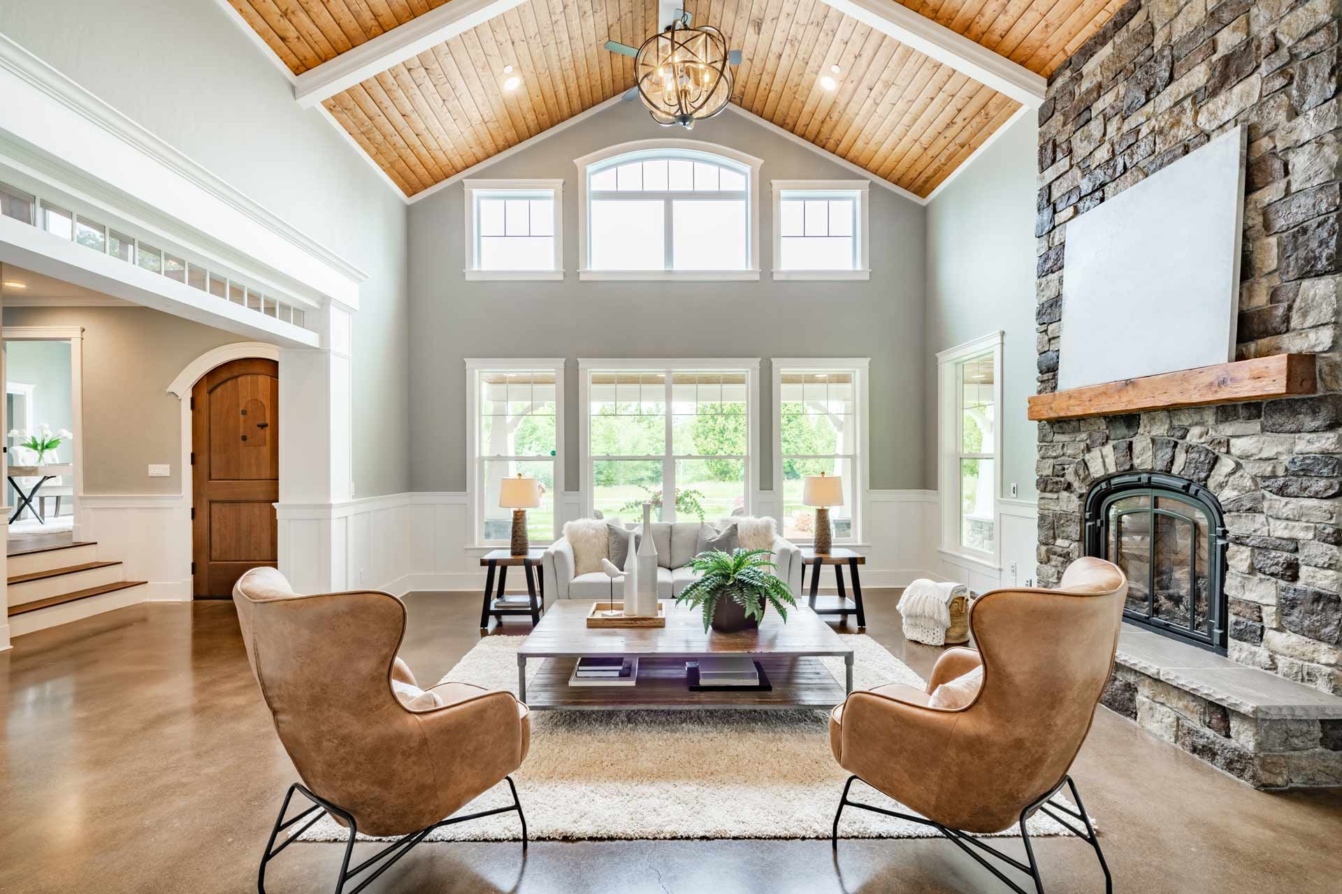 Living room with stone fireplace, wooden ceiling, and two brown armchairs facing each other.