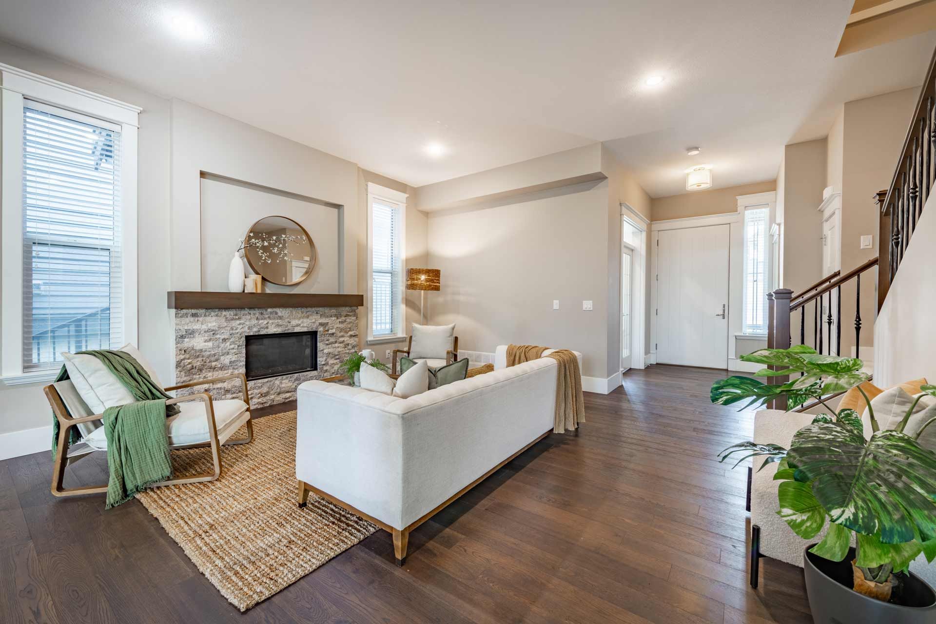 Bright living room with fireplace, white sofa, hardwood floors, and potted plant.