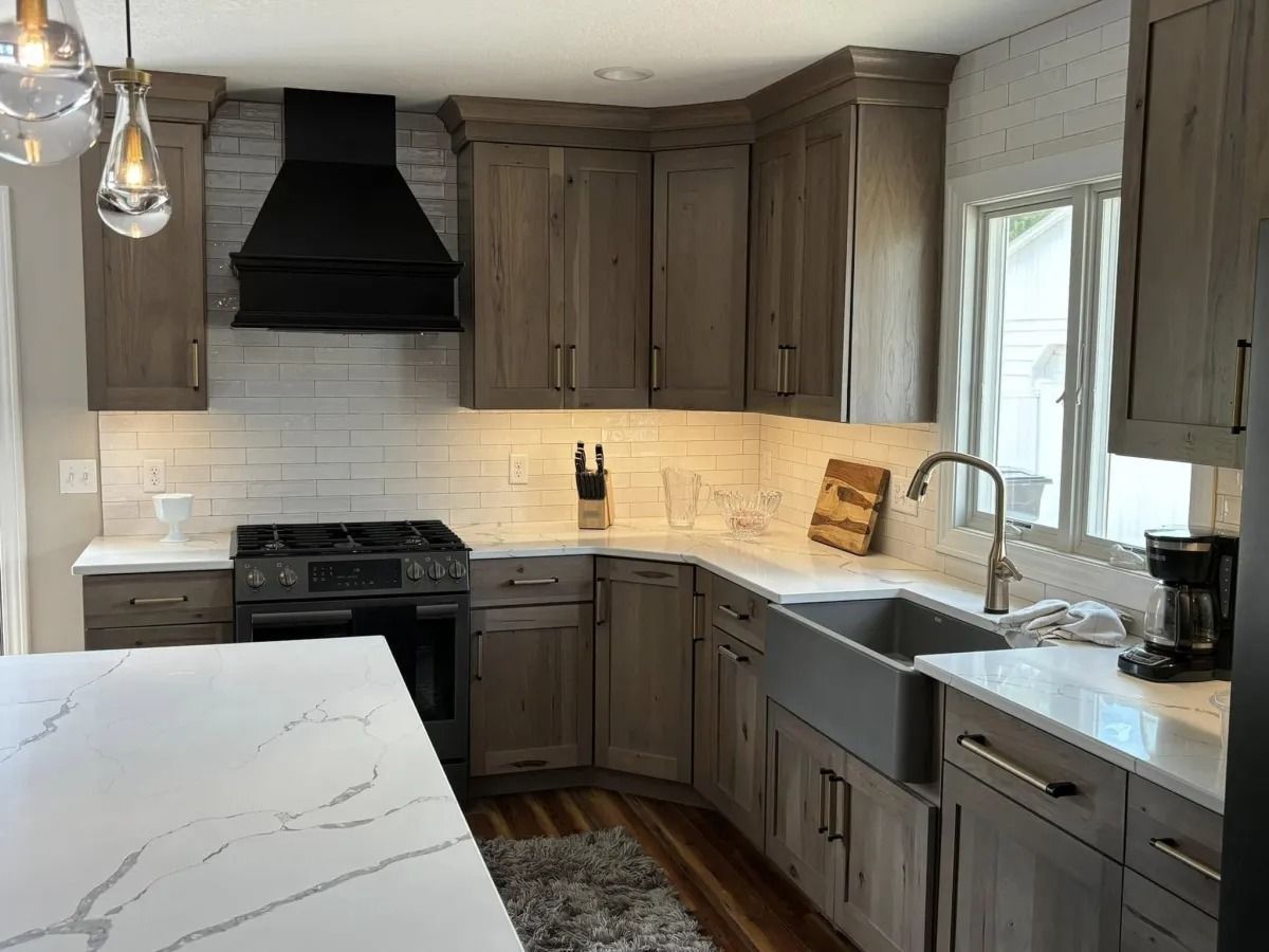 Kitchen with gray wooden cabinets, white countertops, and stainless steel sink.