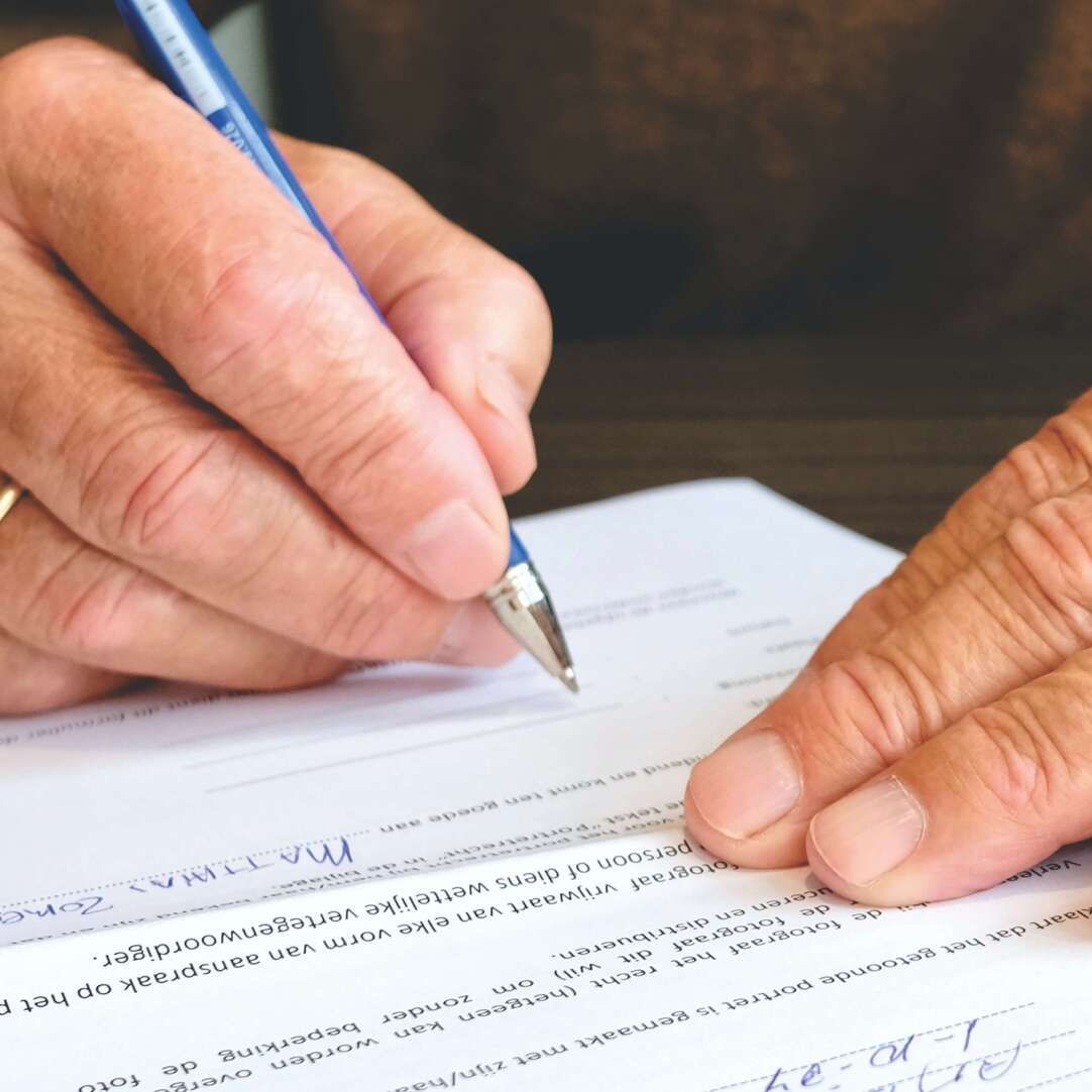 A person is writing on a piece of paper with a pen