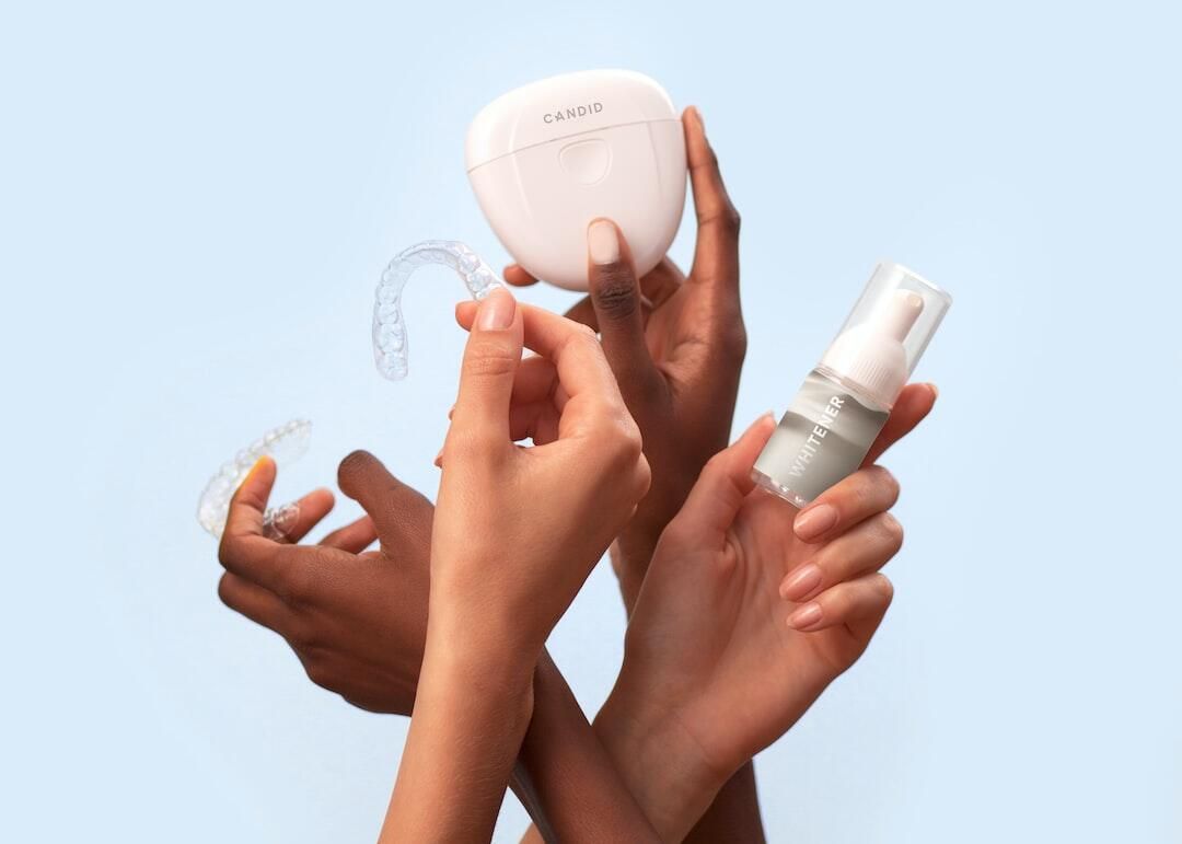 Hands holding skincare products against a light blue background