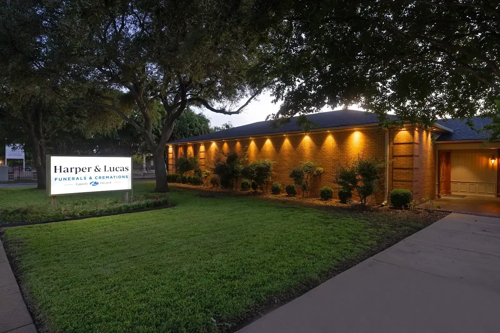 A dignified brick funeral home at dusk, illuminated by warm lights