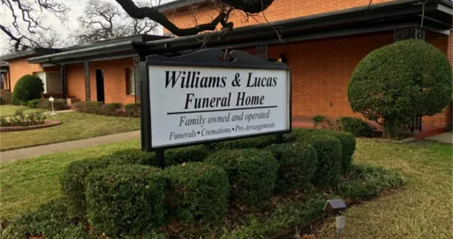 A sign for williams and lucas funeral home is in front of a building.