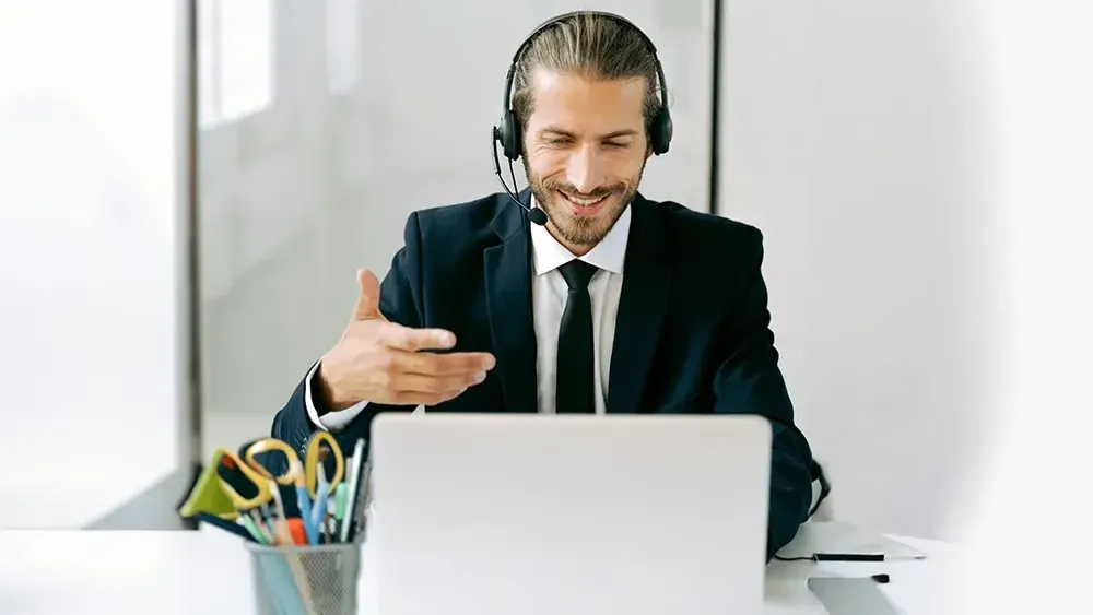 A man wearing headphones is sitting in front of a laptop computer.
